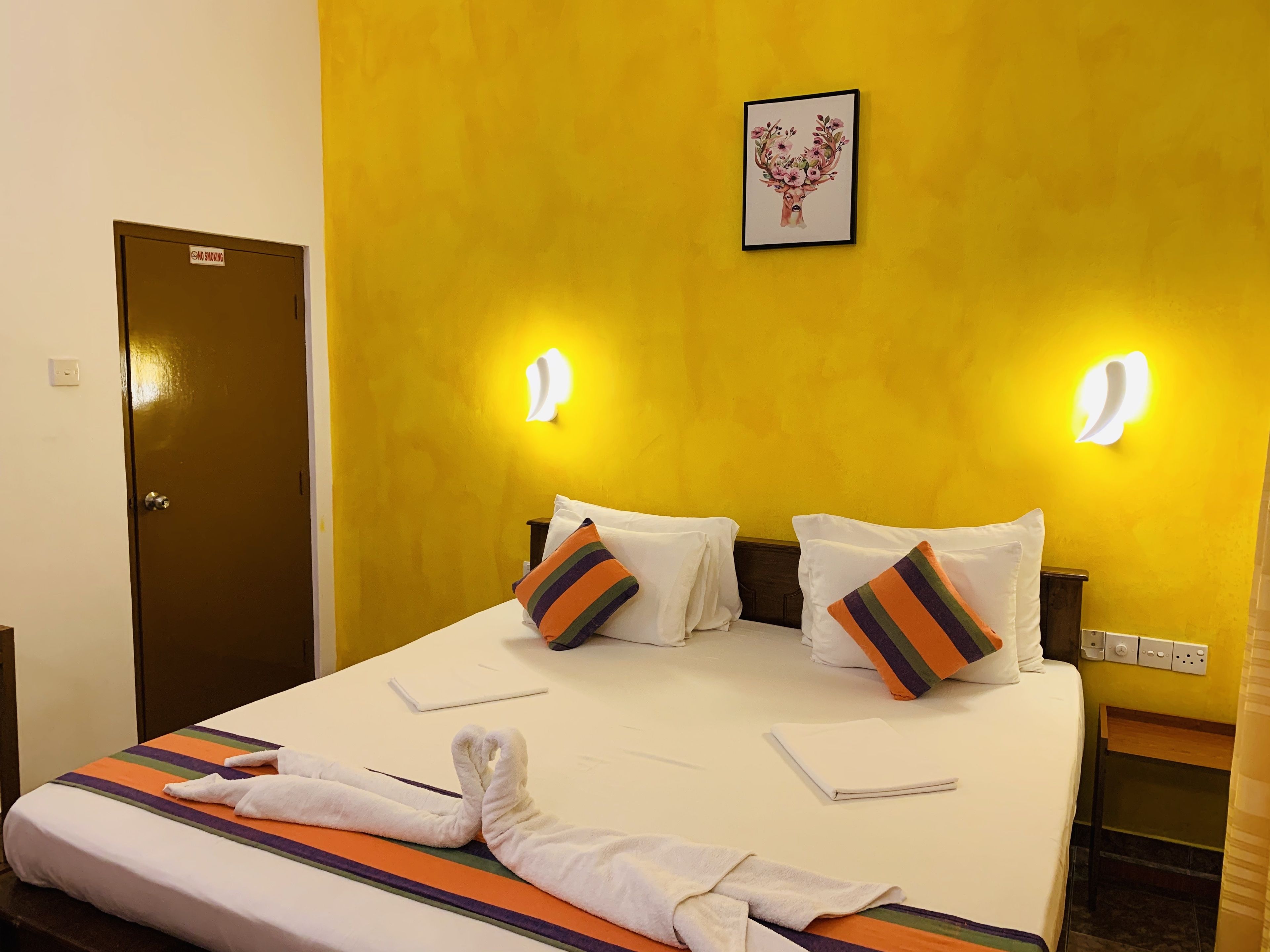 Una habitación de hotel con una cama, dos almohadas, una toalla y una puerta.