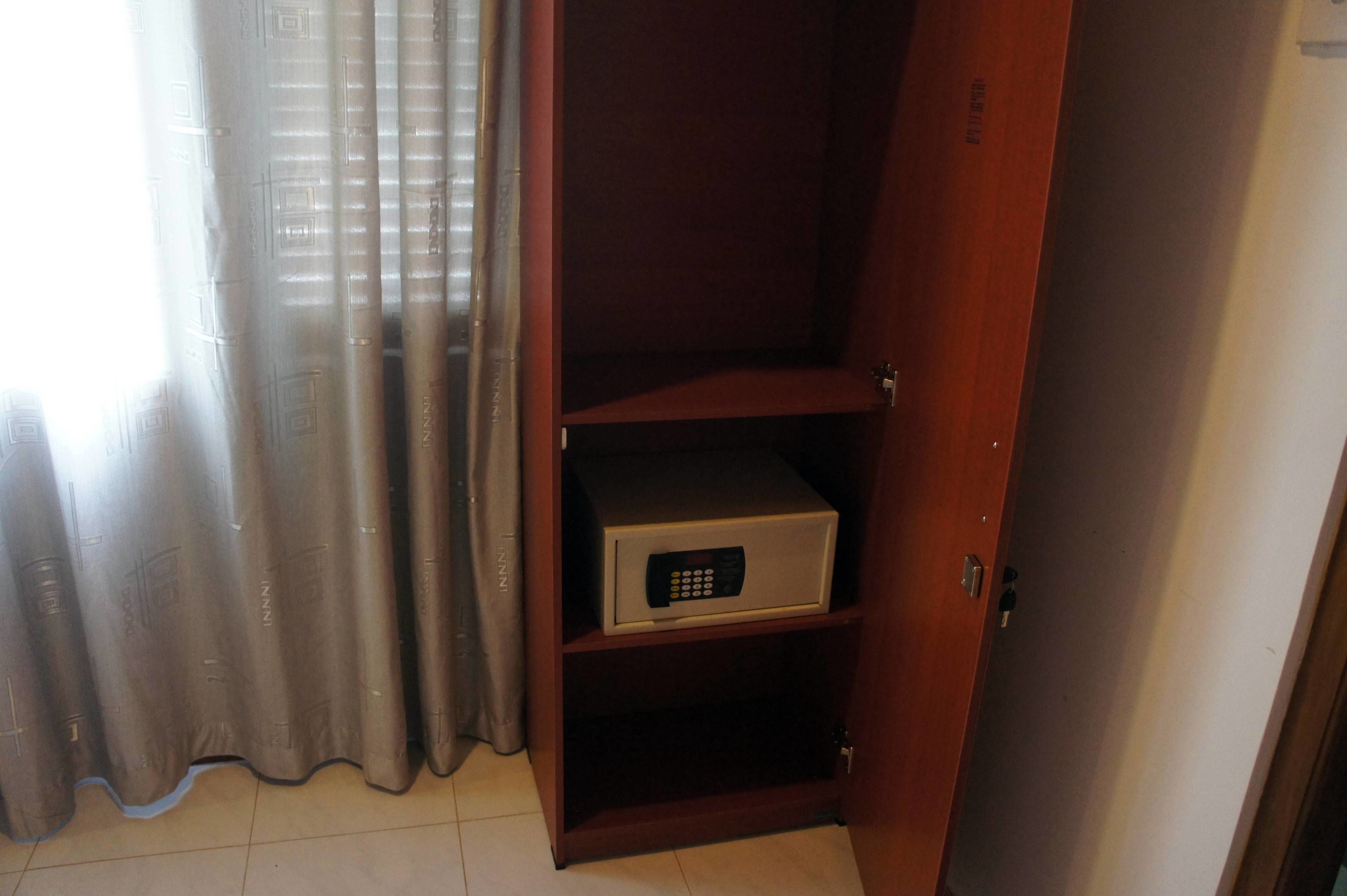 A wooden wardrobe with a microwave on the lower shelf.