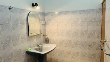 A bathroom with a sink, mirror, and shower.