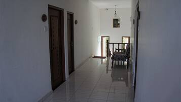 A hallway with a wooden door, a bench, and a hanging light fixture.
