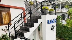 A staircase with black railings leading to a white wall with the name "SAM'S" in blue letters. - Sam's Guest House (Unawatuna)