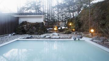 A serene outdoor pool area with a clear view of the surrounding landscape, including a traditional building and a rocky terrain.