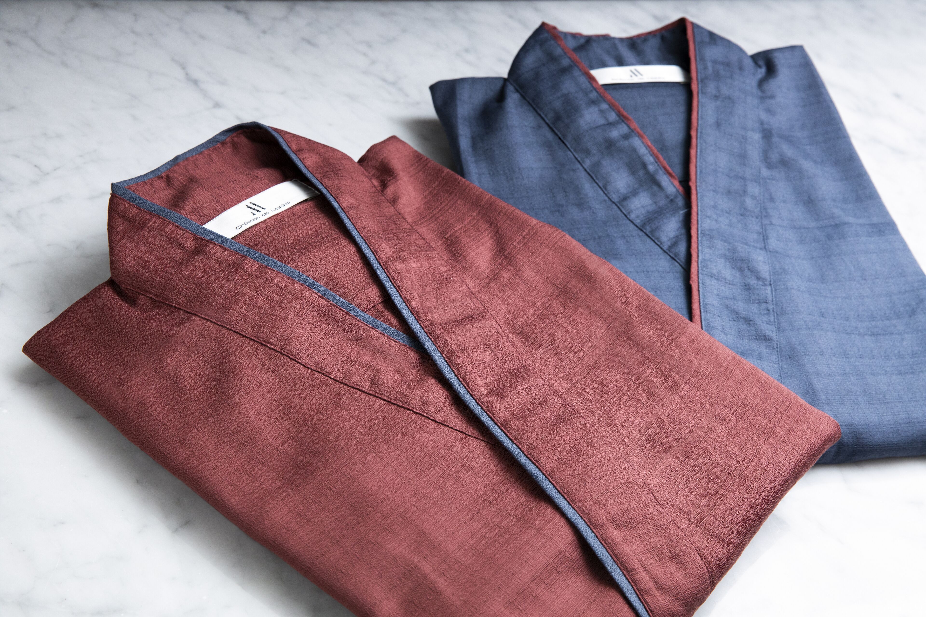 Dos camisas dobladas con cuidado, una roja y otra azul, con una etiqueta visible que indica una marca específica.