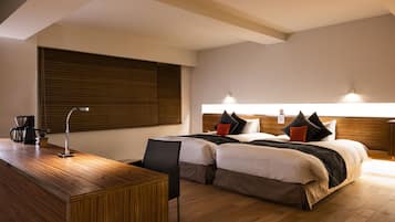 A hotel room with two beds, a wooden desk, and a coffee maker.
