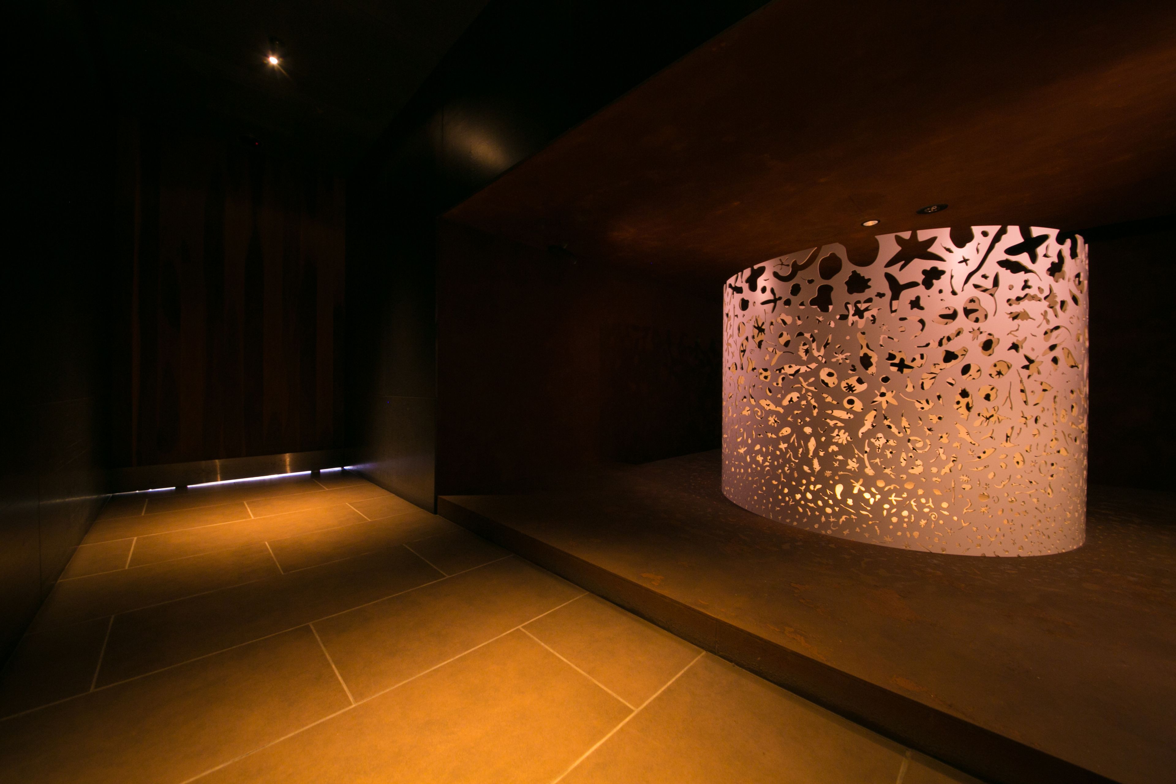 A modern interior with a decorative cylindrical light fixture and a tiled floor.