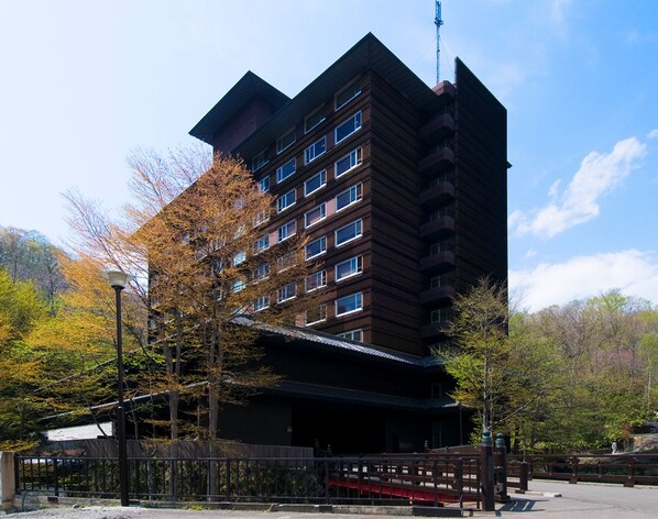 A multi-story hotel with a modern architectural design, featuring a prominent rooftop antenna.