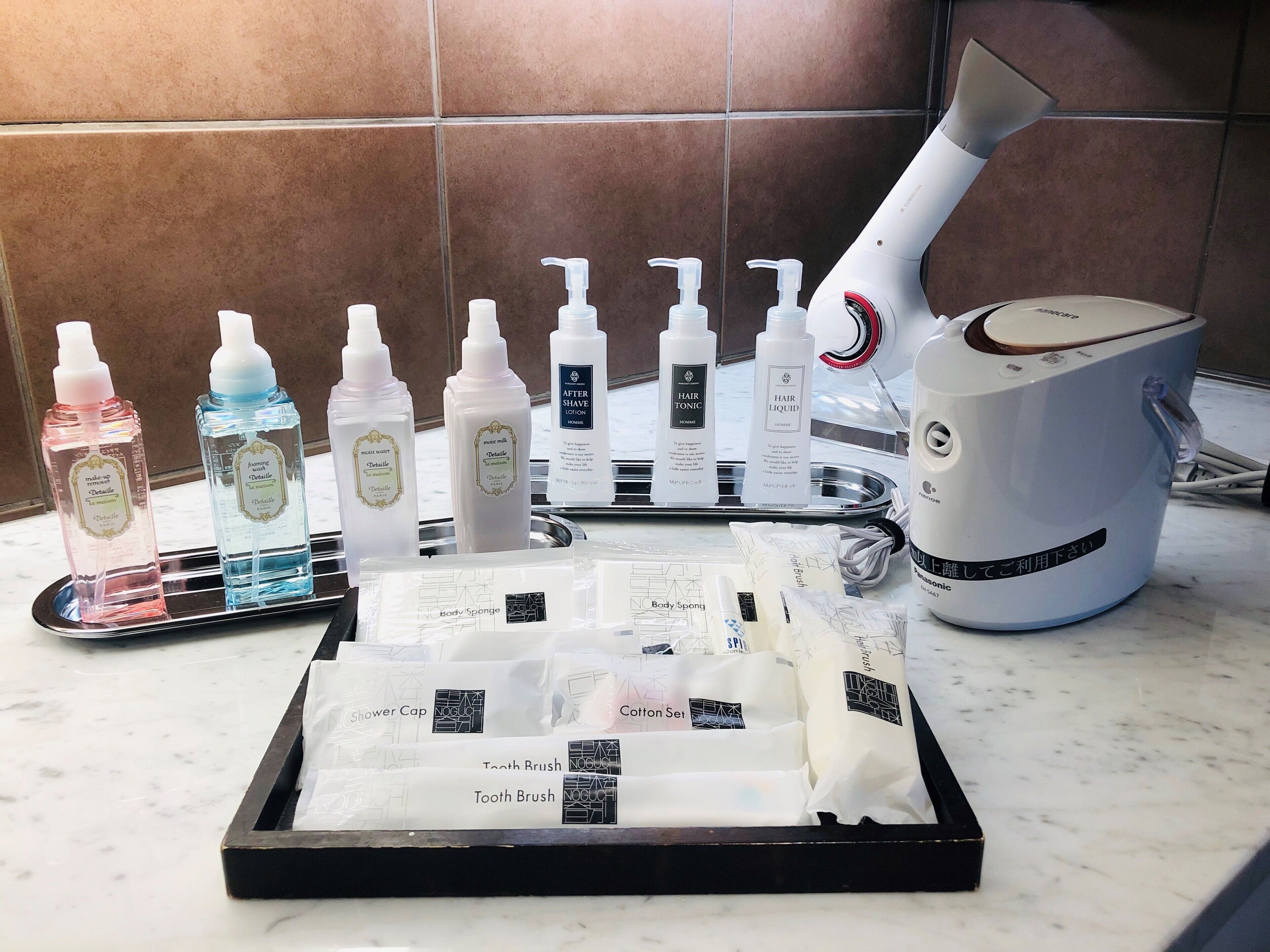 A bathroom counter with various toiletries including bottles of lotion, body sponges, and a hair dryer.