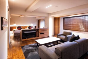 A modern living room with a sofa, a coffee table, a TV, and a kitchen area in the background.