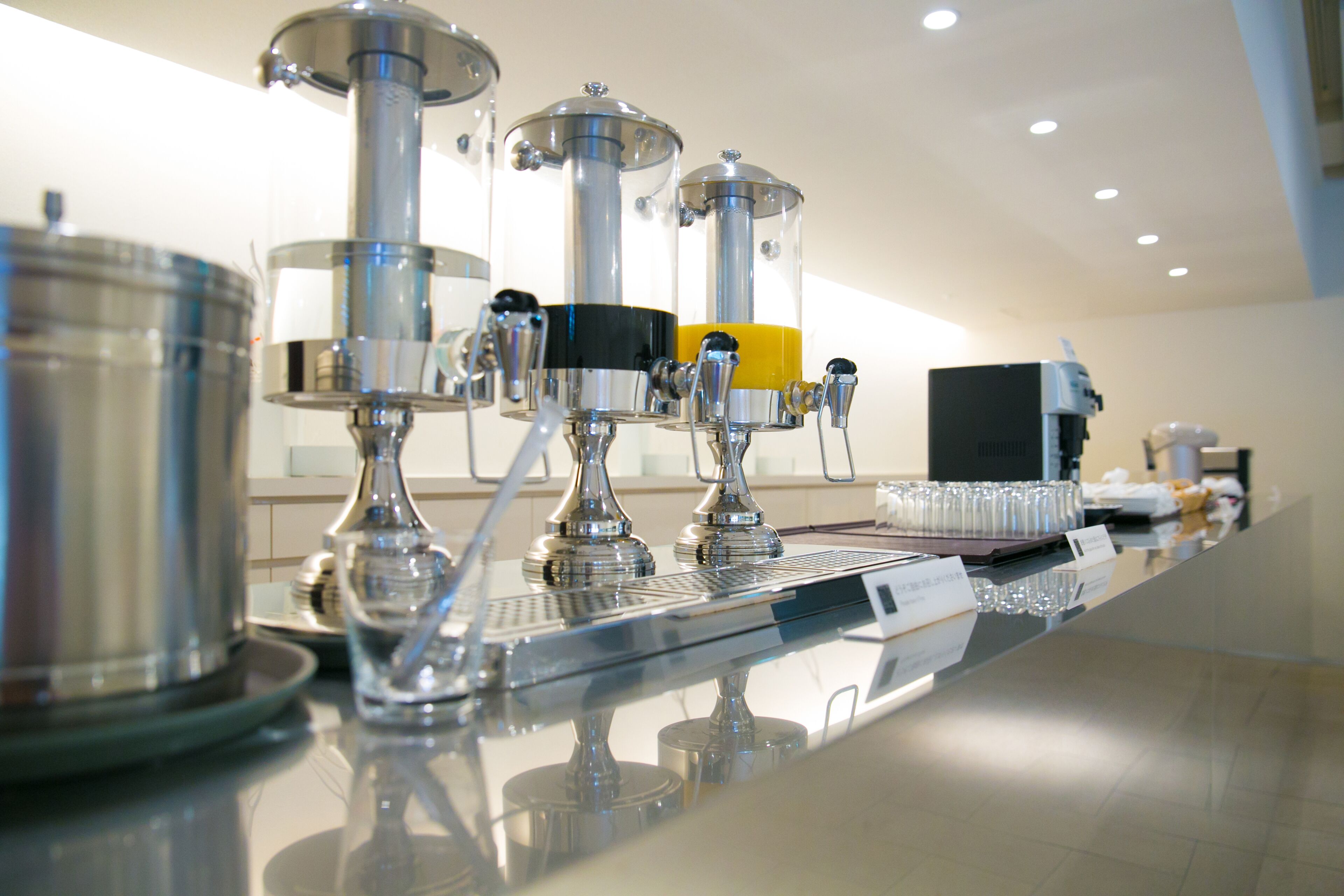 Zona de bar con equipo de acero inoxidable, incluyendo una cafetera y un dispensador de bebidas.