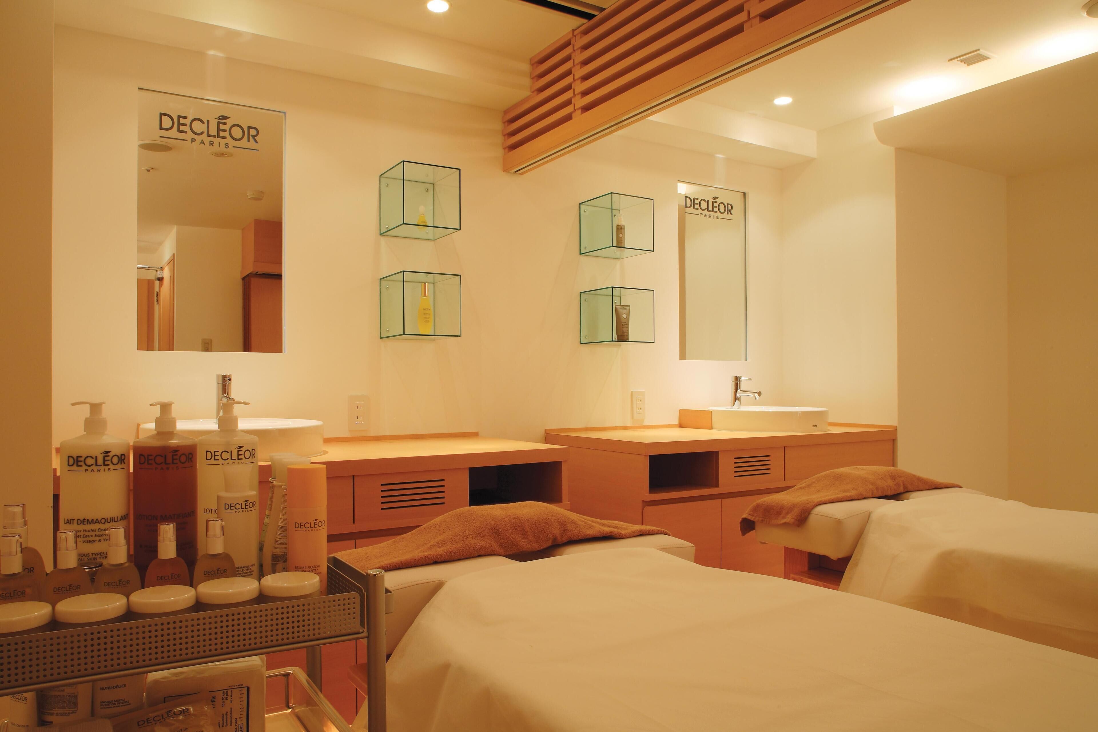 A hotel room with two beds, a large mirror, and a vanity with toiletries.