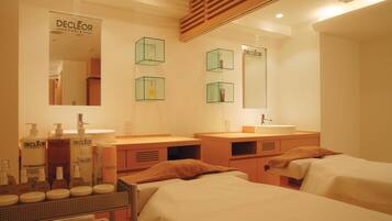A hotel room with two beds, a large mirror, and a vanity with toiletries.