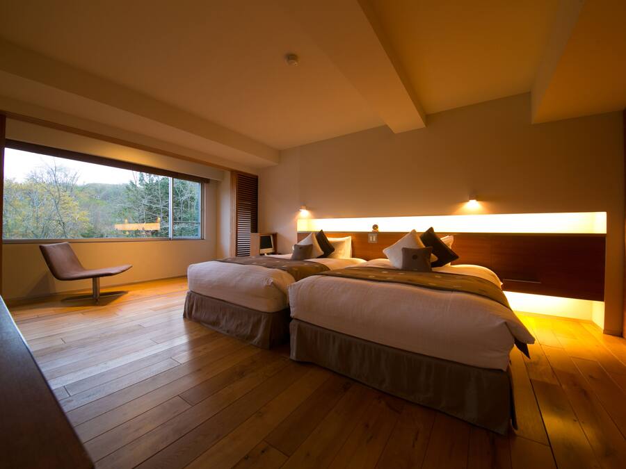 A modern bedroom with two beds, a desk, and a chair.