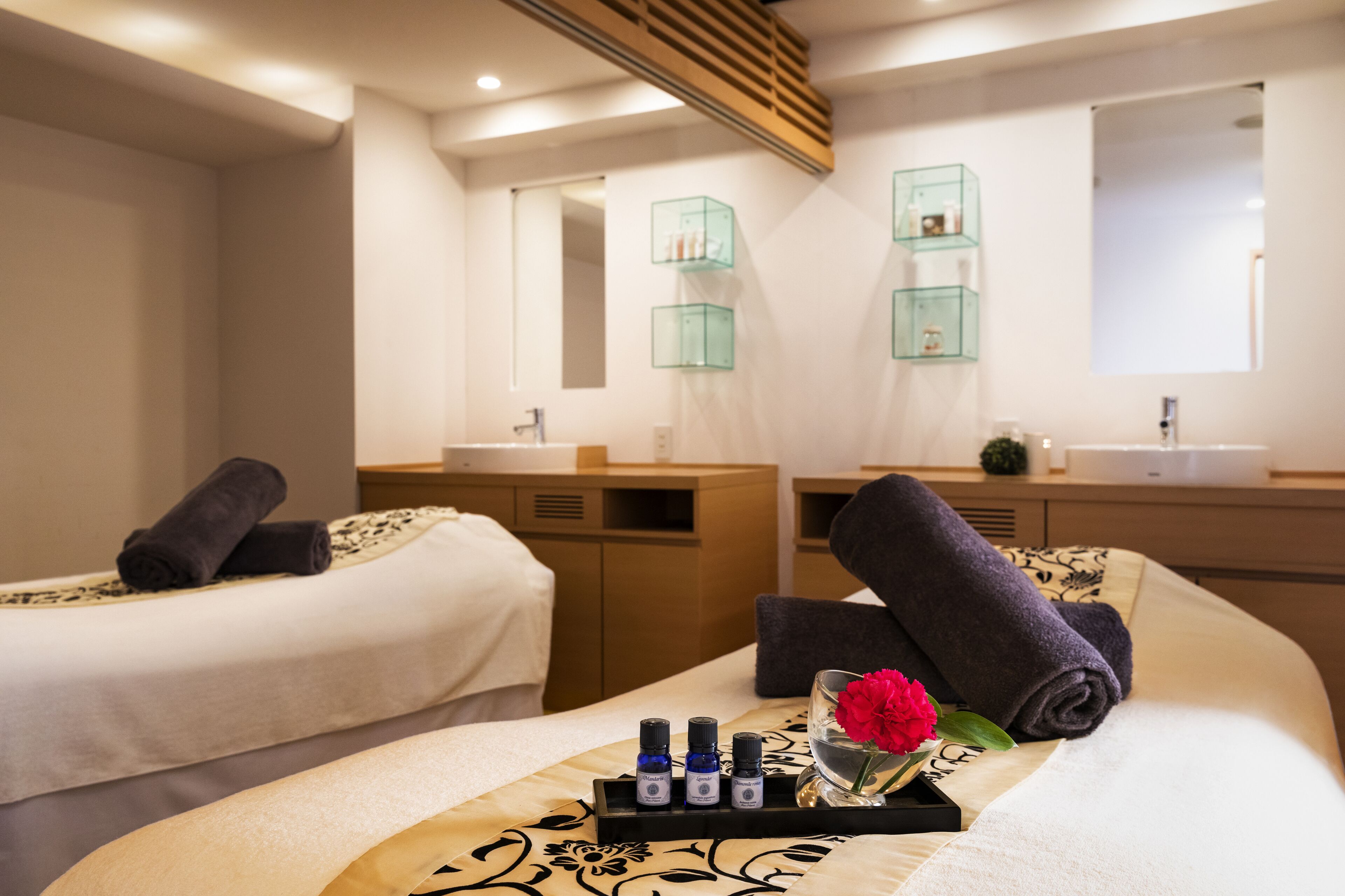 A hotel room with two beds, a vanity with a mirror, and a tray with toiletries.
