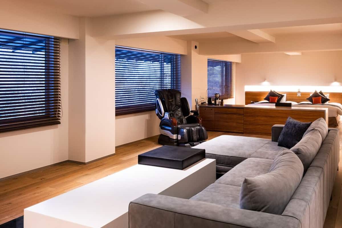 A modern living room with a sectional sofa, a massage chair, and a wooden coffee table.