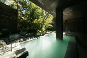 A modern outdoor pool area with a stone pathway, surrounded by rocks and greenery. - Bourou NOGUCHI Noboribetsu - Adult Only (Noboribetsu)