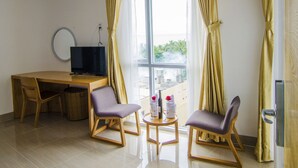 A hotel room with a wooden desk, two chairs, a television, and a window with curtains. - Sailing Hotel (Phu Quoc)