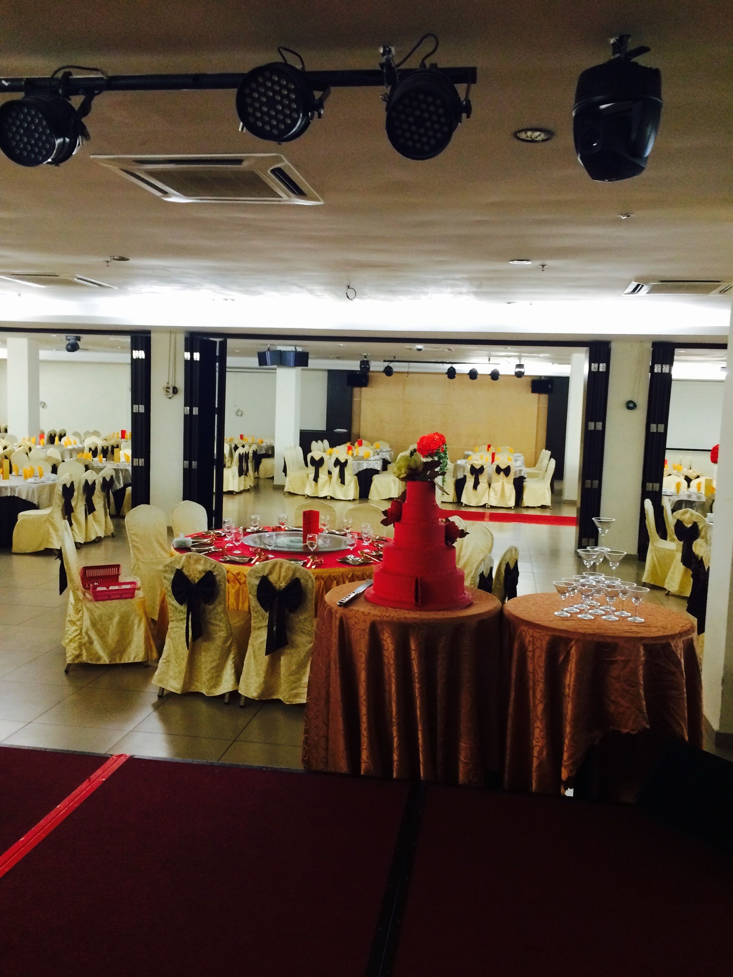 A banquet hall with round tables, chairs, and a stage.