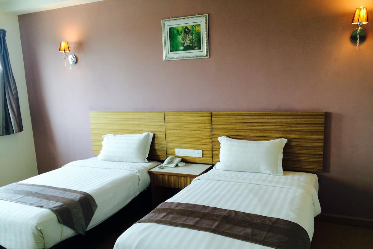 A hotel room with two beds, a wooden headboard, a bedside phone, and a wall-mounted picture.