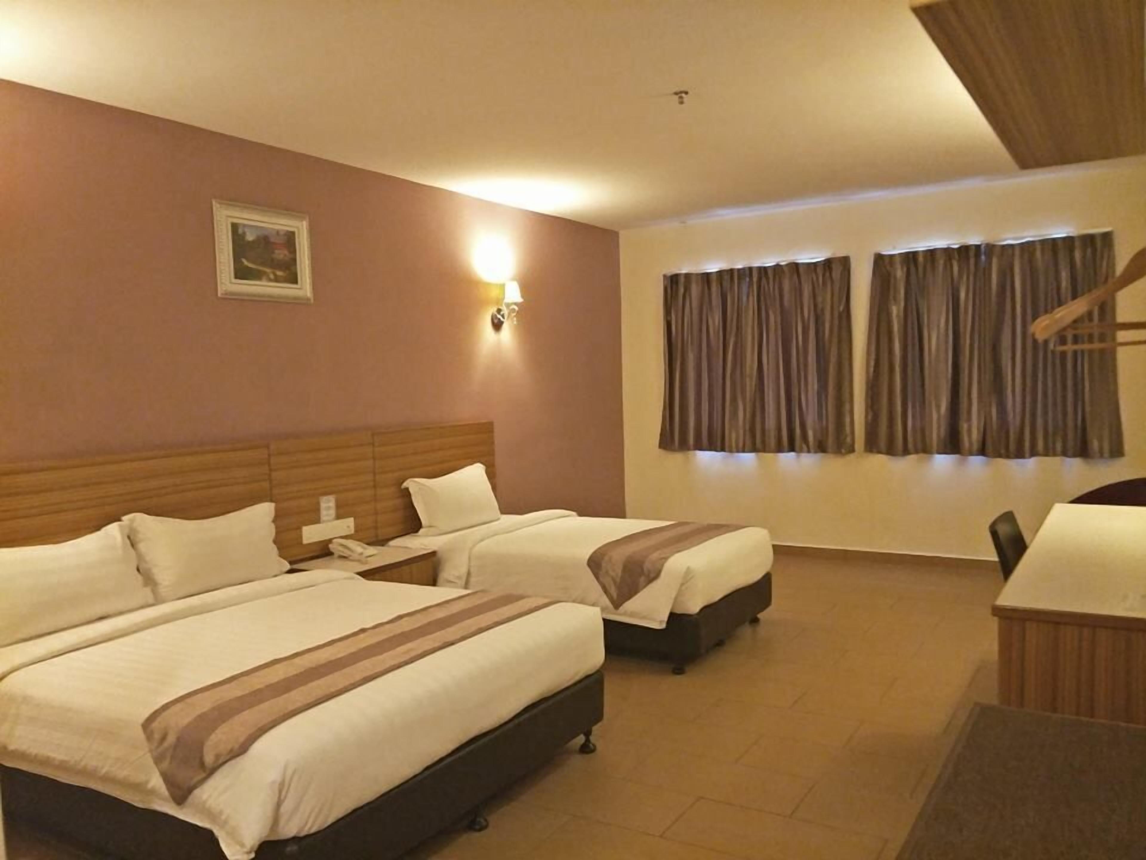A hotel room with two beds, a desk, a chair, a telephone, and a window with curtains.
