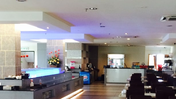 A restaurant with a long counter, tiled floor, and multiple tables and chairs.
