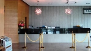A reception area with a counter, two chandeliers, and a brick wall.
