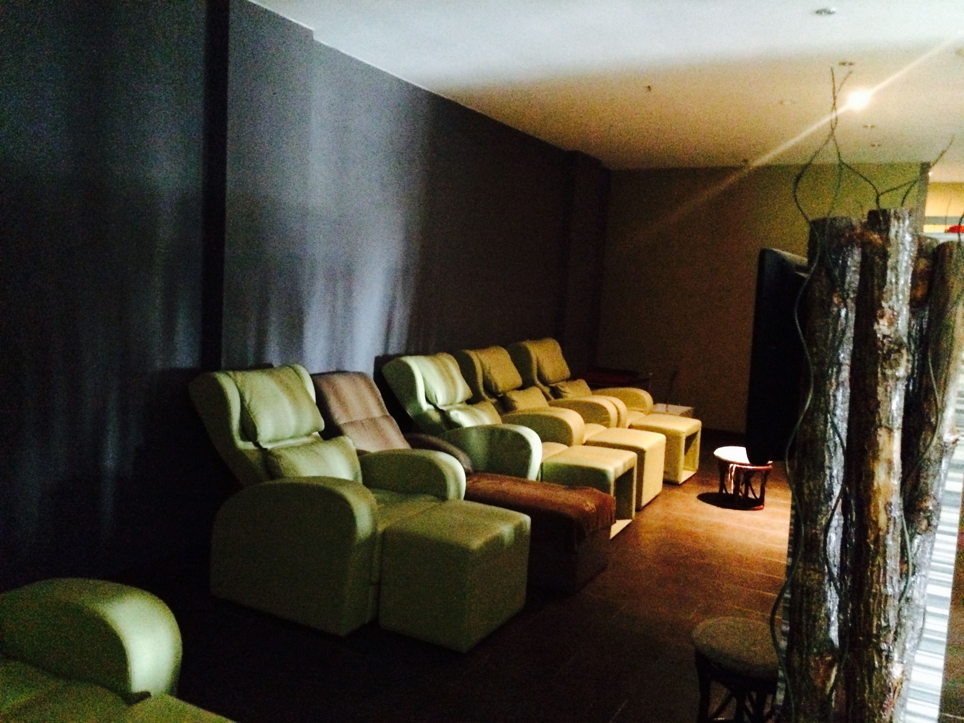 A dimly lit room with a row of massage chairs and a small table.