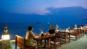 Una pareja cenando en una mesa de madera con vistas al océano y una isla distante.