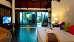 Habitación de hotel con cama, televisión, zona de comedor y vistas al exterior.