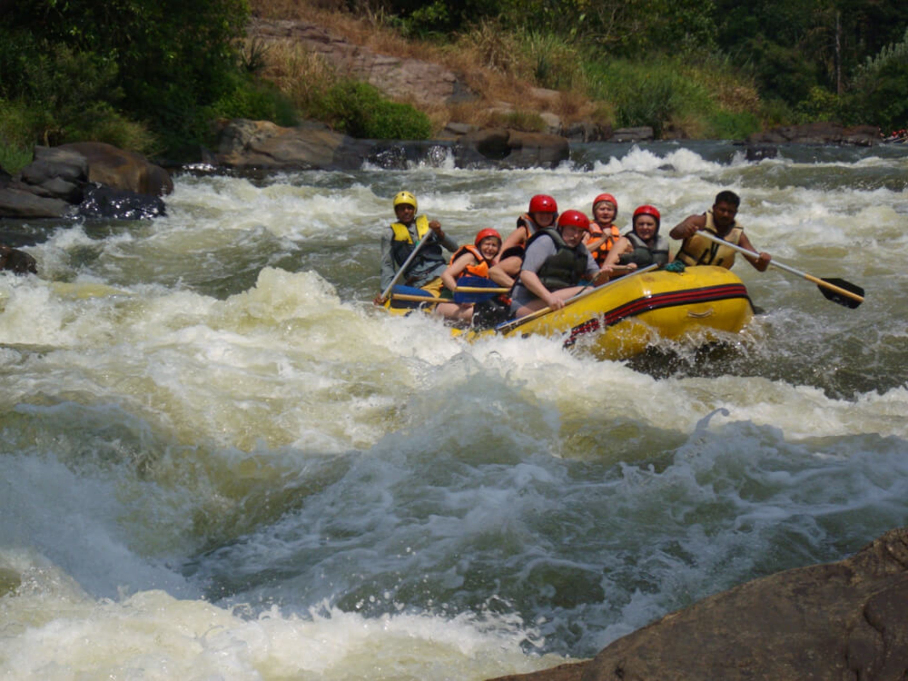 A group of people in a yellow raft navigating through a river with rapids.