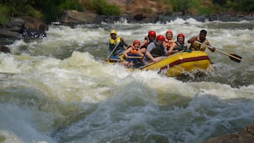 A group of people in a yellow raft navigating through a river with rapids.