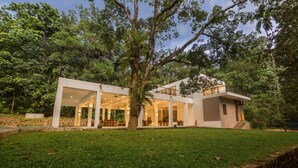 A modern house with a spacious patio, large windows, and a well-maintained lawn. - Palmstone Retreat - Kithulgala (Kithulgala)