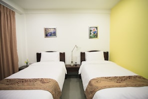 A hotel room with two beds, a nightstand, a lamp, and two framed pictures on the wall. - Su 22 (Bangkok)