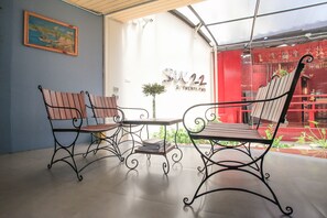 A room with two wooden chairs and a table, a framed picture on the wall, and a sign reading "SW22". - Su 22 (Bangkok)