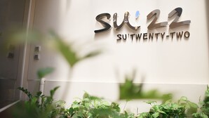 A sign with the text "SU'22" and "SU'TWENTY-TWO" indicating the name and number of a hotel or property. - Su 22 (Bangkok)