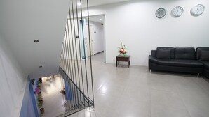 A modern living room with a black sofa, a small table with a vase, and three wall clocks. - Su 22 (Bangkok)