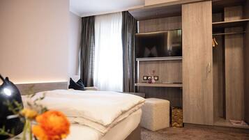 Une chambre d’hôtel moderne équipée d’un grand lit, d’une armoire, d’une télévision et d’une table de chevet.