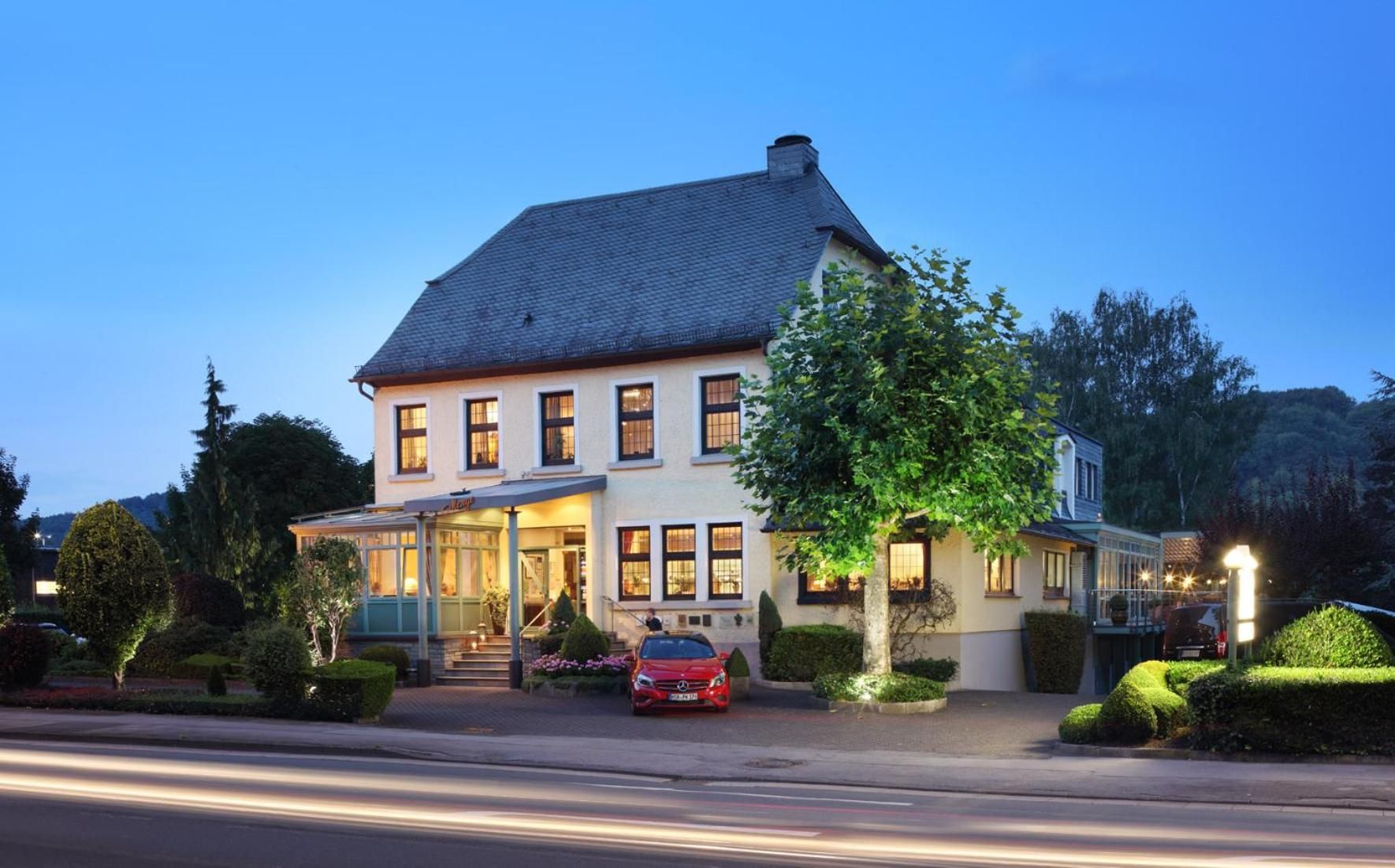A two-story building with a large entrance, a car parked in front, and well-maintained landscaping.