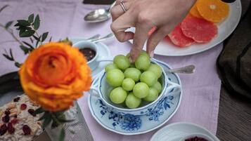 Una mesa con un bol de uvas verdes, un plato con mandarinas en rodajas y un bol de compota de frutos rojos.