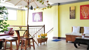 A room with a wooden table and chairs, a sofa, and a bed. There is a window and a door. - Vanilla Place (Chiang Mai)