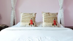 A bed with two pillows, one featuring the Colosseum and the other a woman in a red dress. - Vanilla Place (Chiang Mai)