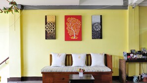 A living room with a wooden sofa, a blue mat, and three wall art pieces. - Vanilla Place (Chiang Mai)