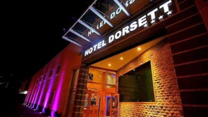 Het uiterlijk van Hotel Dorsett met verlichte borden en een gevel van baksteen.