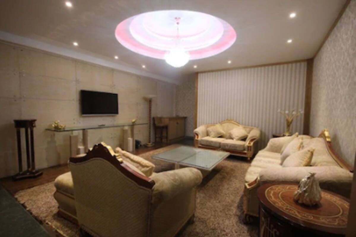 Una sala de estar con dos sofás, una mesa de centro, un televisor y una lámpara decorativa en el techo.