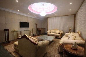 Una sala de estar con dos sofás, una mesa de centro, un televisor y una lámpara decorativa en el techo.