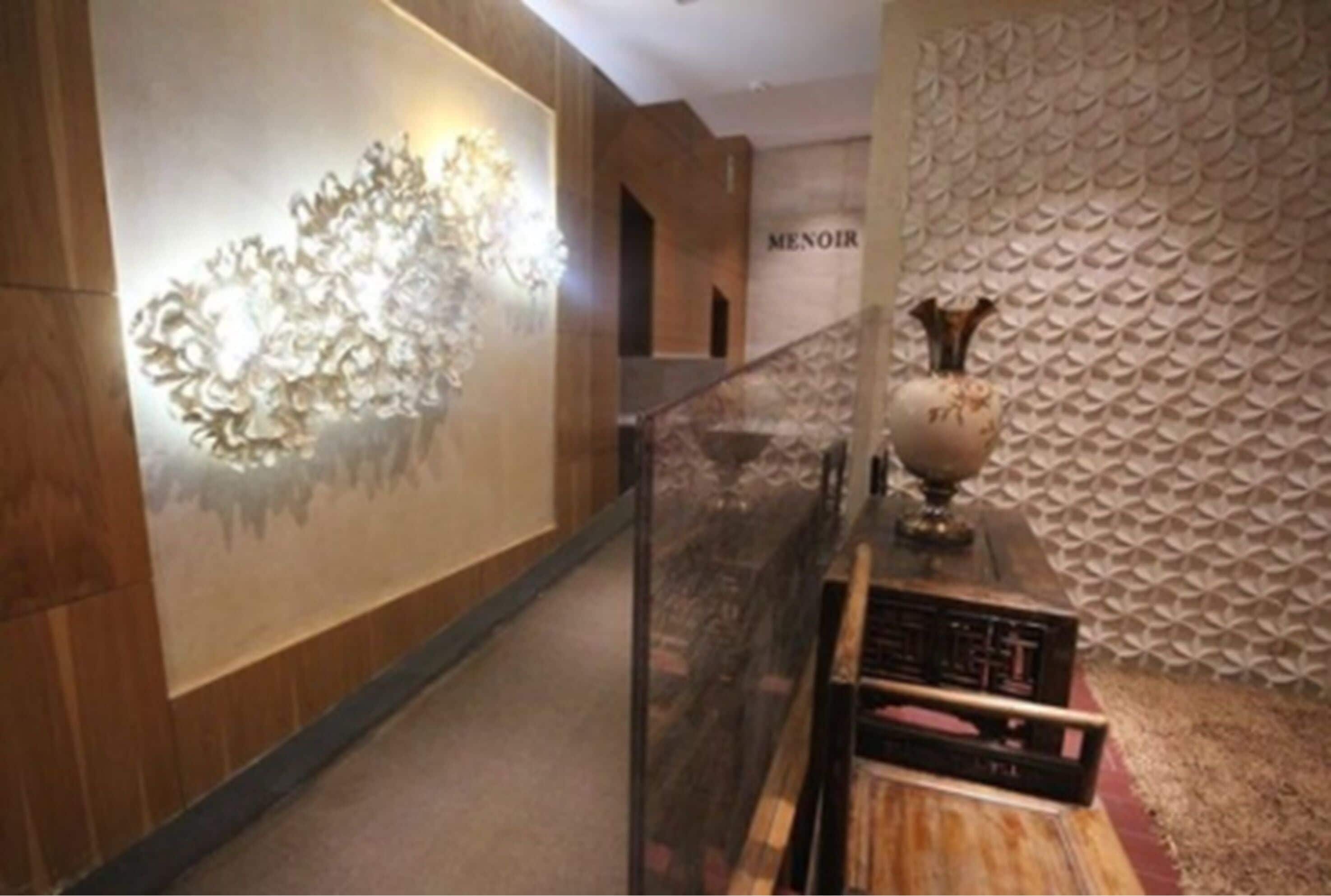 Un pasillo con pared de madera, una lámpara decorativa y una pared texturizada con la palabra "MENOIR".
