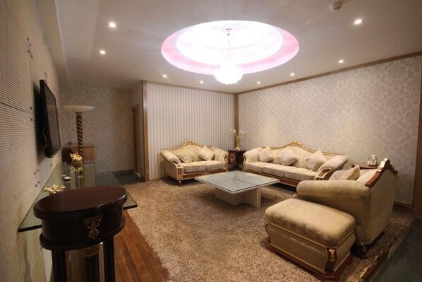 A living room with a sofa set, a coffee table, and a TV mounted on the wall. - Hotel Menoir Dorsett (Leganes)