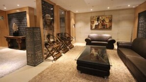 Een moderne woonkamer met een leren bank, een glazen salontafel en een decoratieve open haard.