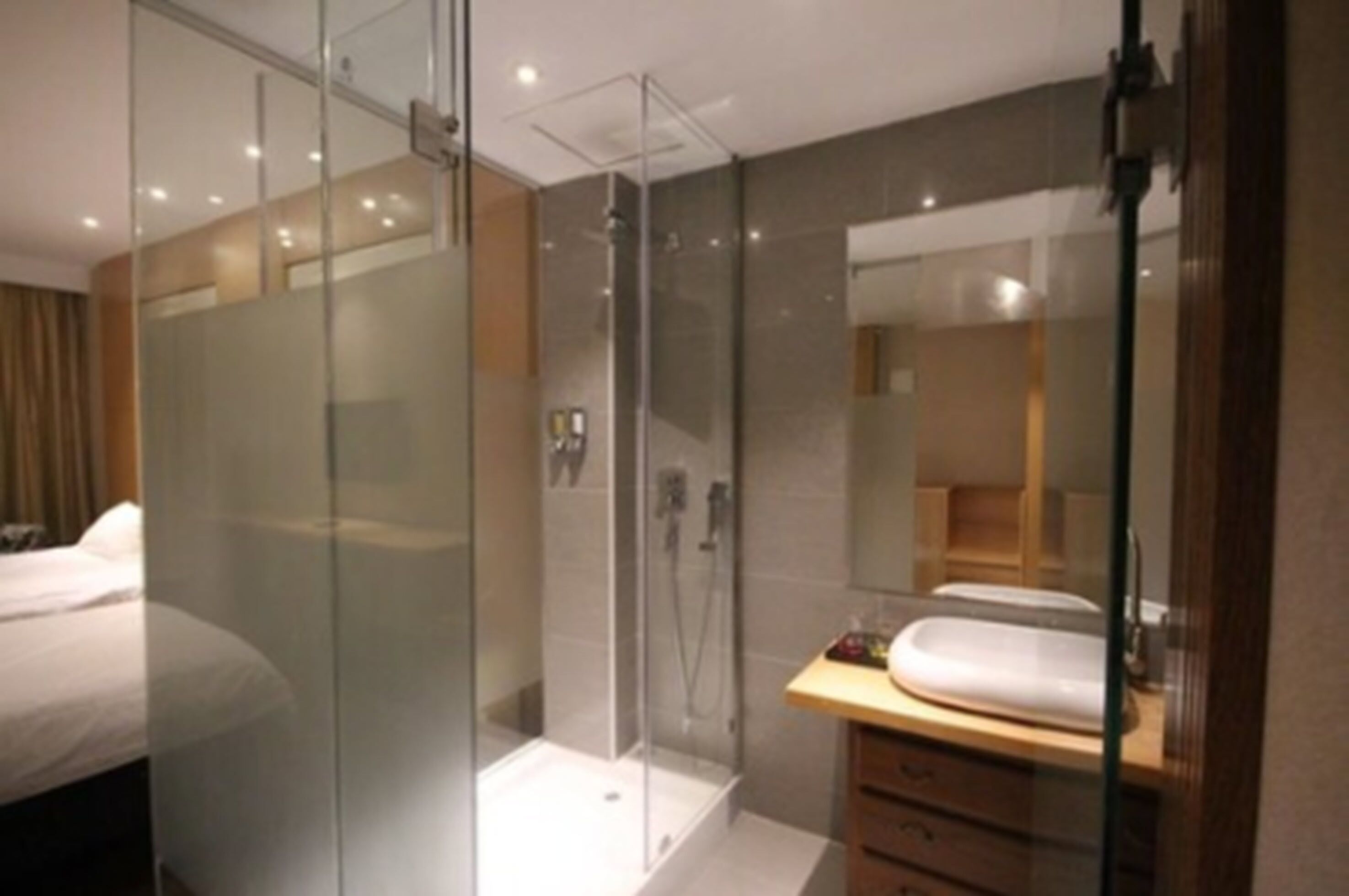 A modern bathroom with a glass-enclosed shower, a wooden vanity, and a large mirror.