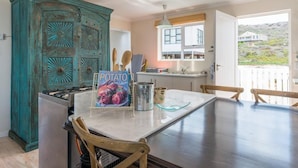 A kitchen with a large island, a teal cabinet, and a book titled "The Popular Potato" on the island. - Casa Bertella (Yzerfontein)