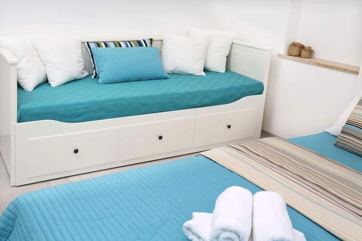 Un dormitorio con cama, mesita de noche y un estante pequeño.